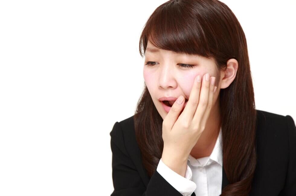 頬を抑えて痛そうにする女性