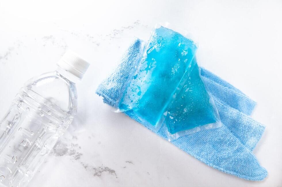 水の入ったペットボトルと保冷剤、タオル