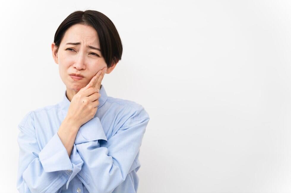 頬を抑えて痛そうにする女性