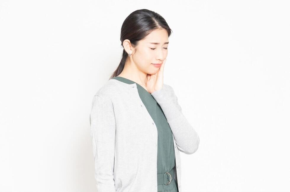 頬を抑えて痛そうにする女性