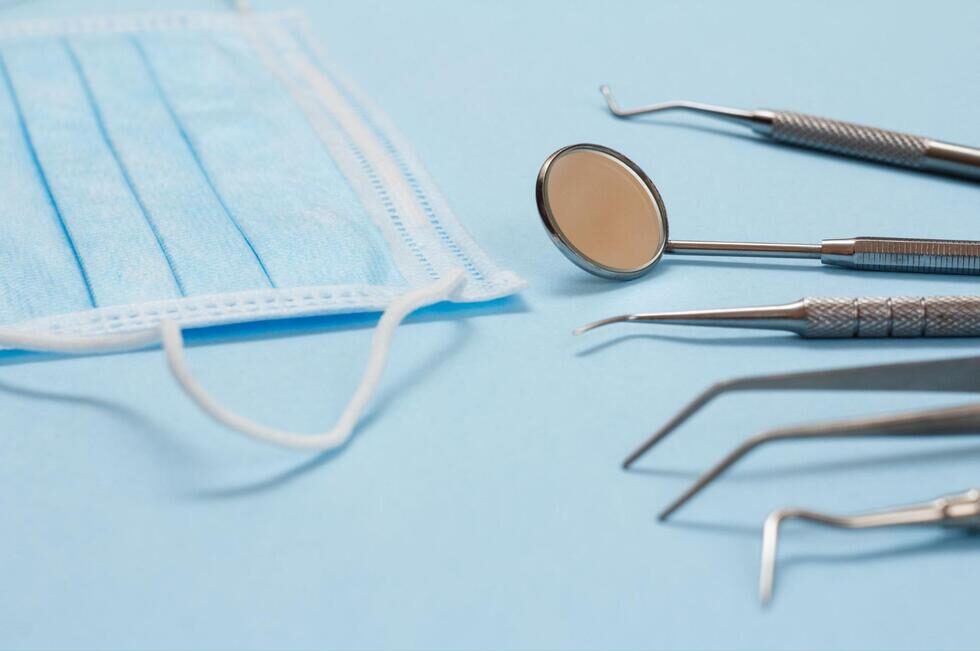 デンタルミラーやピンセットなどの歯科器具とサージカルマスク