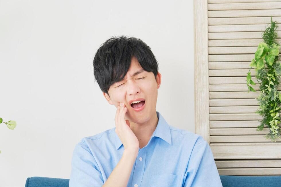 痛そうな表情で頬を抑える男性