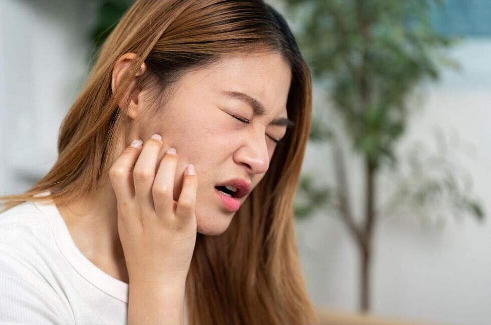 右顎を押さえて痛そうにする女性