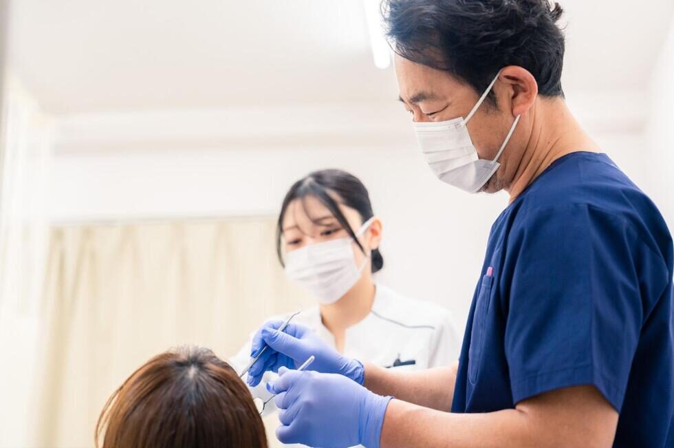 デンタルミラー等の器具を使用して診察をする歯科医師