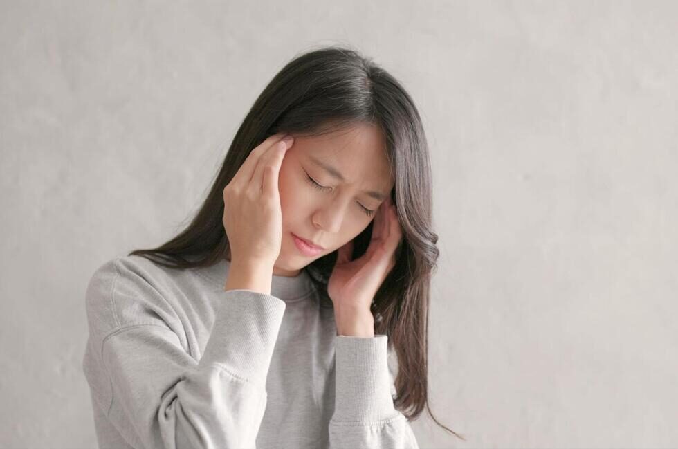 両手でこめかみを押さえる女性