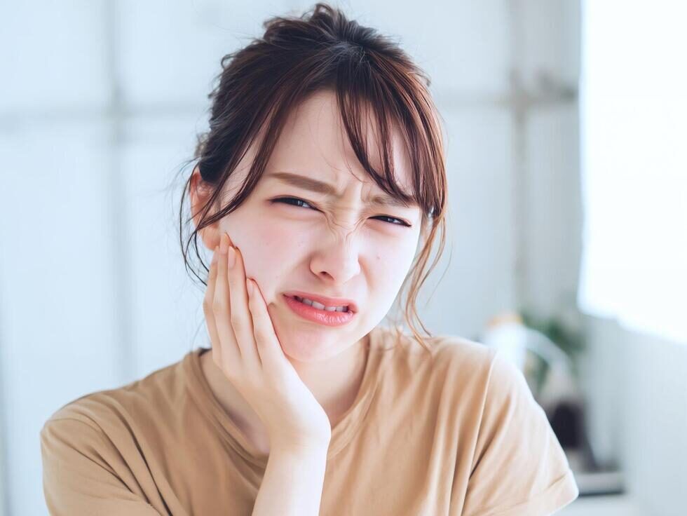 顎を手で押さえて痛そうにする女性