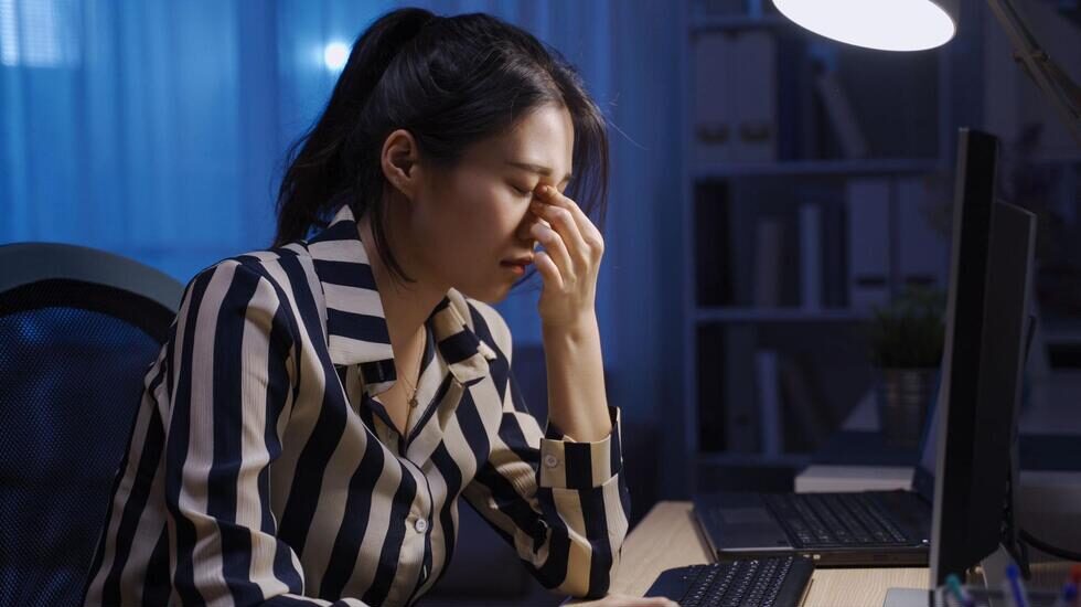 PC作業をしながら眉間を押さえる女性