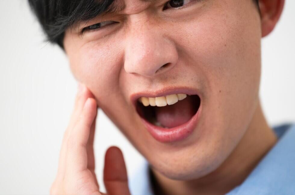 頬を抑えて痛そうにする男性