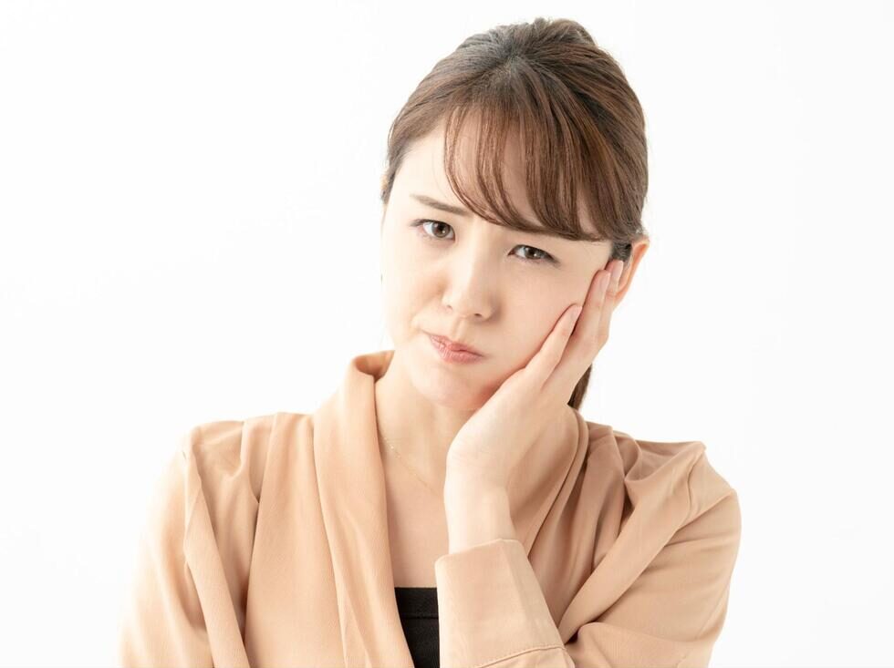 左頬を手で押さえて痛そうにする女性