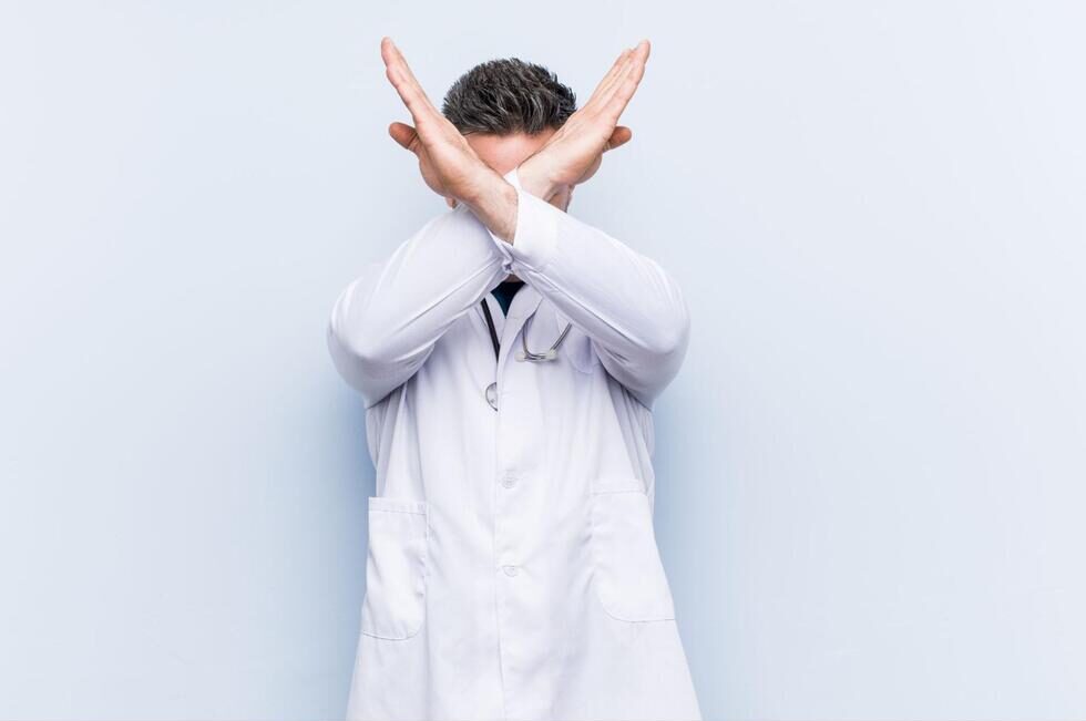 両手でバツ印をつくる歯科医師